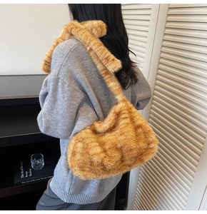 Detail of soft mustard yellow plush tote bag worn by a model in a cozy indoor setting