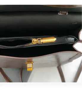 Close-up of a brown leather backpack featuring a smooth gold zipper and a turn-lock closure