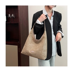 Detail shot of the khaki suede texture and leather brand tag on the mini square bag