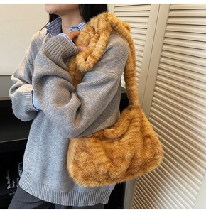Detailed texture of orange cat pattern plush tote bag carried by a model in a cozy interior