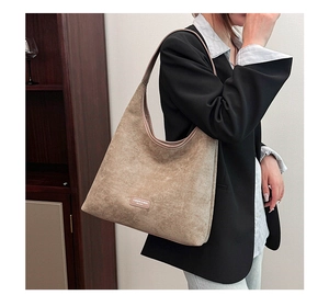 Close-up of the large tan faux suede hobo bag showing its soft texture and logo detail