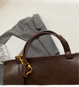 Detail of vintage dark brown leather bag with golden chain and sturdy round handles
