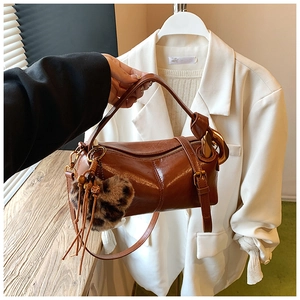 Detailed close-up of brown glossy leather bag with gold hardware and leopard heart charm