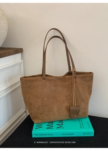 Dettaglio di una borsa tote vintage in pelle opaca marrone caramello su un libro