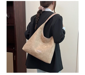 Detail of tan suede shoulder bag with thin straps and white FASHION lettering logo
