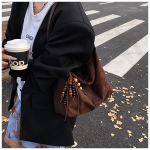 Close-up of deep brown suede hobo bag with unique wood and resin beaded tassel pendant