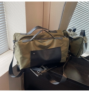Close-up of military green nylon travel bag with black leather straps and metal hardware