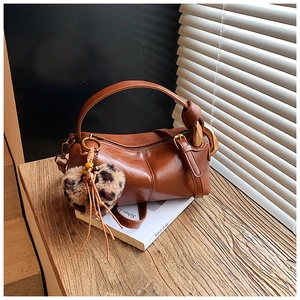 Close-up of vintage brown leather Boston bag with heart charm on wooden desk