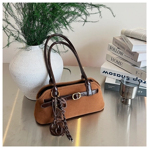 Detail of vintage brown frosted baguette bag with decorative buckle and woven pendant