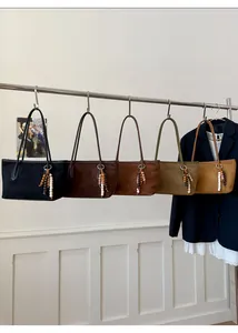 Row of suede handbags in five colors with wooden bead charms and long shoulder straps
