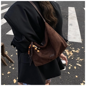Detail of dark brown suede hobo bag with ethnic wooden bead charms on the side