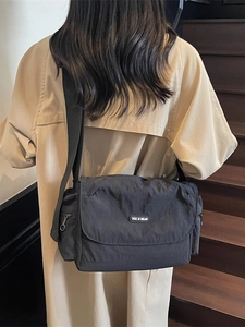 Minimalist black nylon messenger tote bag for women showing a stylish crossbody back view