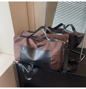 Detailed macro view of deep brown nylon travel bag with premium black leather straps
