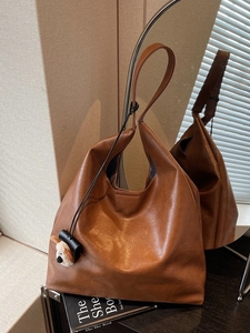 Brown leather large tote bag with shoulder strap and white plush dog charm decoration