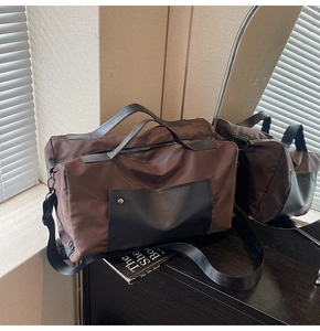 Detail of travel bag showing reinforced leather pocket with studs and adjustable strap