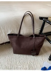 Dettaglio macro della borsa tote in pelle scamosciata marrone scuro con spalline