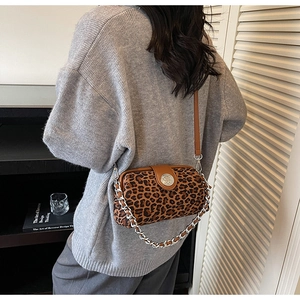 Detail of leopard print crossbody bag with silver chain and brown leather strap on model