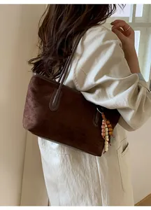 Detail of dark brown suede tote bag with bohemian beaded charms and slim shoulder straps