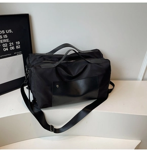 Detail view of large black nylon travel bag with leather pocket on a geometric stand