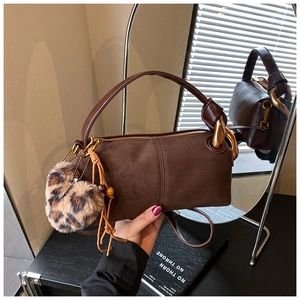 Close-up of brown suede mini Boston bag with gold rings and leopard heart charm