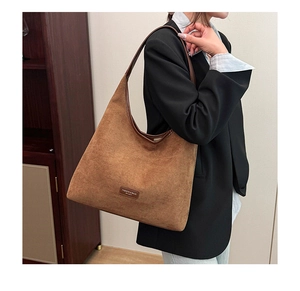Detail view of the brown suede tote bag with FASHION & BAGS branding and leather strap