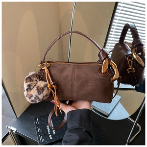 Detail of dark brown faux suede cylinder bag with leopard fur ball and gold ring hardware