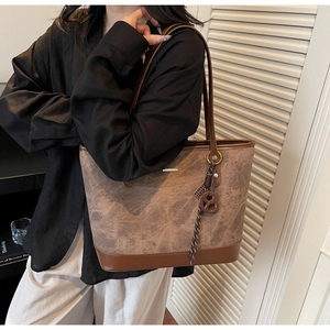 Detail view of retro brown tote bag featuring a round pendant and adjustable shoulder strap