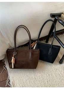 Detail of suede tote bags with retro long fringe tassels and delicate metal ring buckles