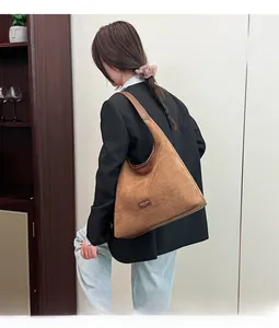 Detail of a large vintage brown suede shoulder bag with leather trim and fashion tag