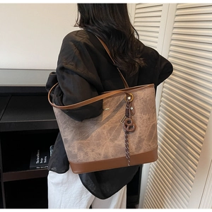 Chic brown tote bag with marble texture and leather straps worn on shoulder in urban setting