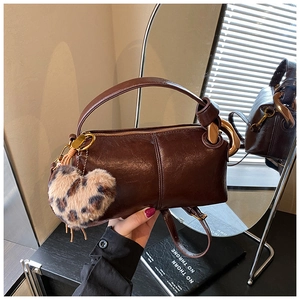 Detail of dark brown pillow bag featuring gold zipper and leopard print heart charm