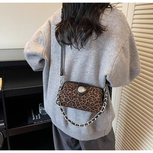 Detail shot of vintage leopard print crossbody bag with silver chain strap on model