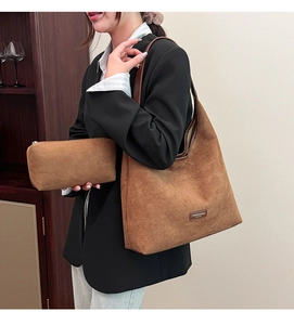 Detail of a brown suede oversized tote bag with matching zippered pouch and vintage logo