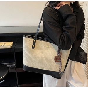 Detailed view of bicolor tote bag with suede texture, black leather trim and vintage charm