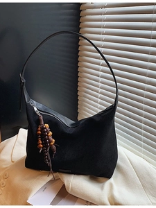 Retro black tote shoulder bag with wooden bead tassel on minimalist blazer background
