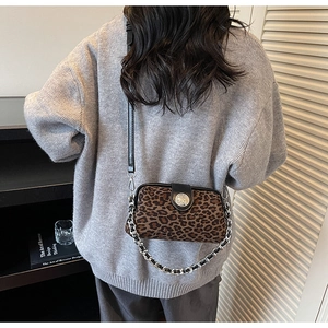 Detail view of leopard print crossbody bag with silver chain and black leather strap