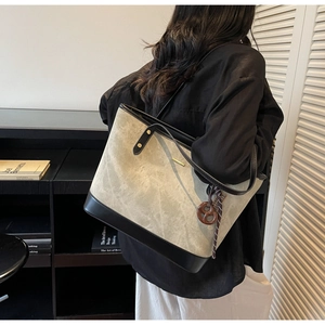 Detail view of large grey tote bag with black strap and decorative brown bow accessory