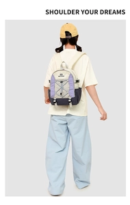 Rear view of model wearing a lightweight color-block outdoor backpack in cream and purple