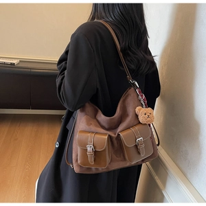 Detail of brown vintage suede tote bag with leather pockets and plush bear charm