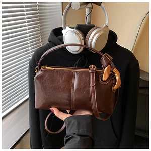 Detail of vintage dark brown oil wax leather cylinder bag with gold metal hardware