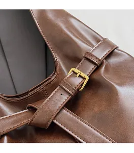 Detail of adjustable gold buckle and premium brown leather texture on a tote bag