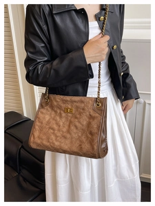 Détail du sac cabas en daim marron avec surpiqûres et chaîne dorée élégante