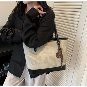 Detail view of large grey tote bag with contrast black leather and gold hardware