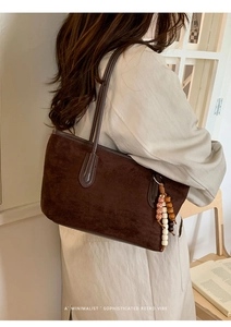 Detail of dark brown suede shoulder bag with ethnic beaded tassel and retro vibe