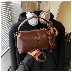 Detail of vintage brown oil wax leather cylindrical bag with antique gold hardware finish
