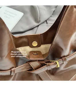 Detail of dark brown tote bag featuring magnetic closure and adjustable strap buckle
