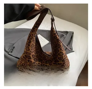 Detailed view of the leopard print pattern and brown leather strap on this retro hobo bag