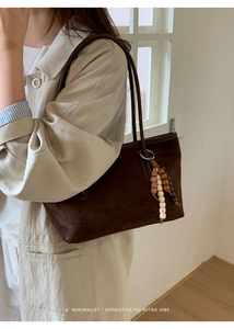 Detail of dark brown suede tote bag with ethnic beaded tassel and minimalist design