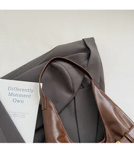 Detail of smooth shoulder strap and glossy brown leather texture on a vintage tote bag
