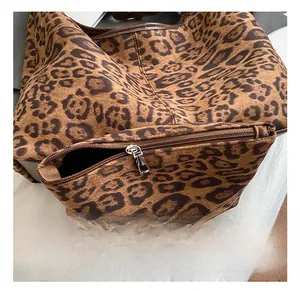 Detailed close-up of leopard print tote featuring silver metal zipper and soft suede texture